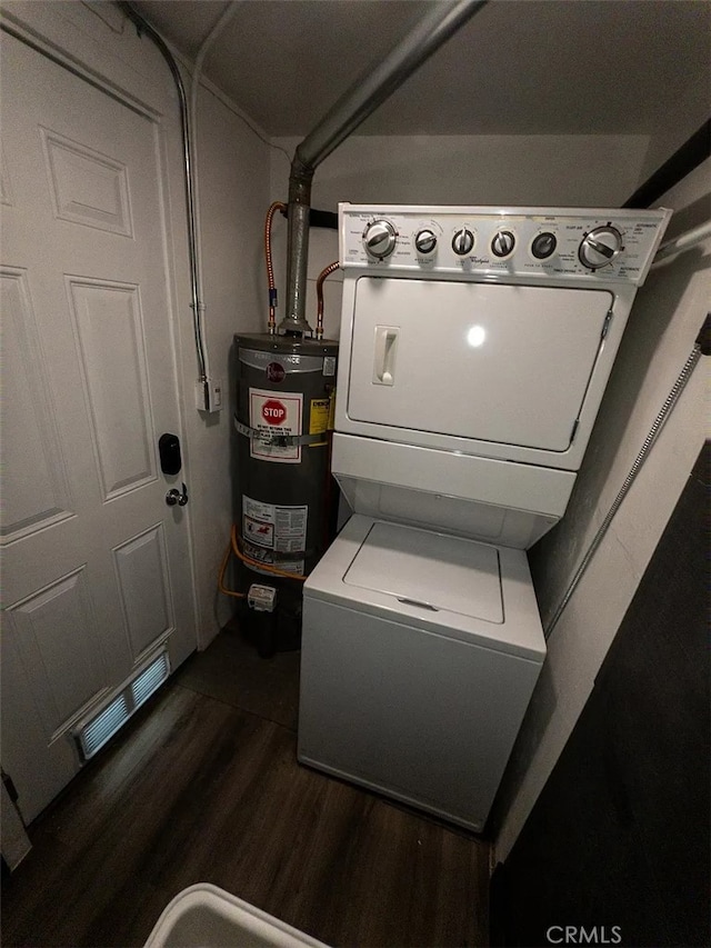 clothes washing area with secured water heater, stacked washer / dryer, and dark hardwood / wood-style floors