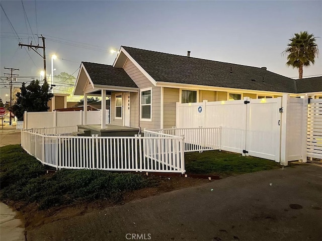 view of front of home featuring roof with shingles, a gate, and fence private yard