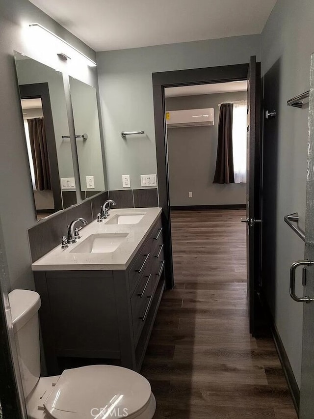 bathroom featuring a wall mounted air conditioner, vanity, hardwood / wood-style flooring, an enclosed shower, and toilet