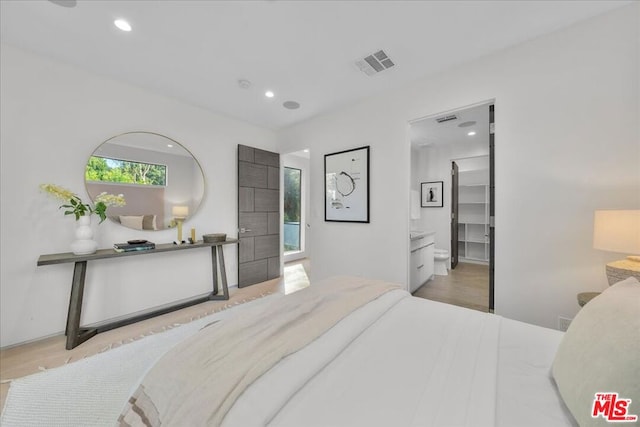 bedroom with light hardwood / wood-style floors and ensuite bath