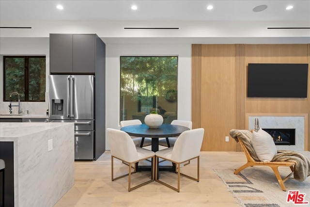 dining area featuring a premium fireplace, sink, and light wood-type flooring