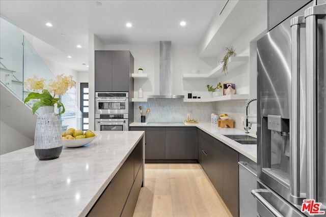 kitchen featuring sink, appliances with stainless steel finishes, backsplash, light stone counters, and extractor fan