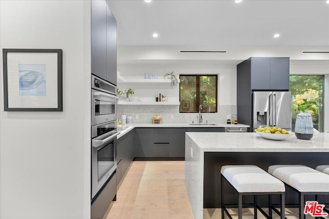 kitchen featuring high quality fridge, tasteful backsplash, sink, a kitchen breakfast bar, and light stone counters