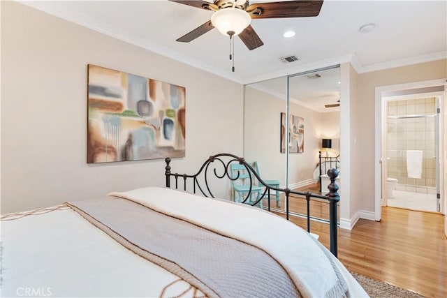 bedroom featuring ceiling fan, connected bathroom, a closet, wood-type flooring, and ornamental molding