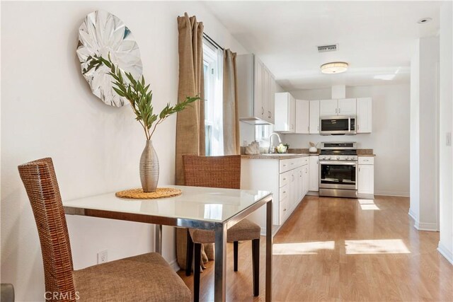 kitchen featuring sink, white cabinetry, appliances with stainless steel finishes, and light hardwood / wood-style flooring