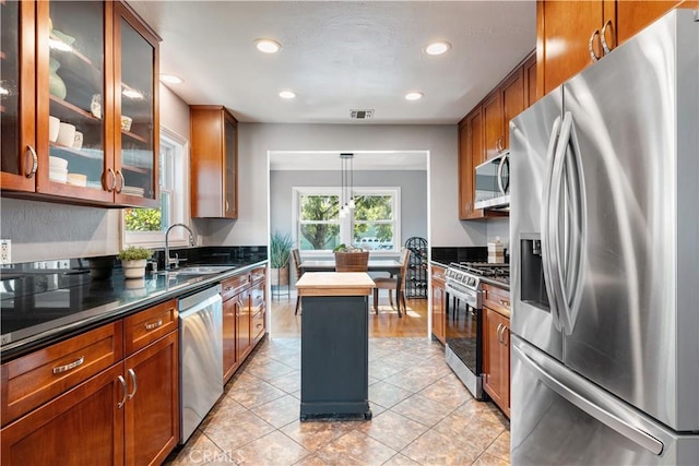 kitchen with decorative light fixtures, sink, appliances with stainless steel finishes, and light tile patterned floors