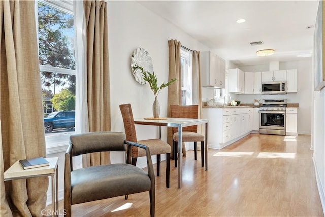 kitchen featuring white cabinetry, stainless steel stove, light hardwood / wood-style floors, and sink