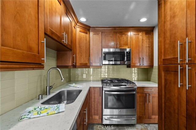 kitchen featuring light stone counters, appliances with stainless steel finishes, sink, and decorative backsplash