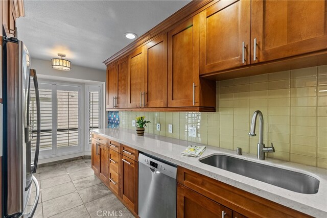 kitchen featuring appliances with stainless steel finishes, light stone countertops, sink, and backsplash