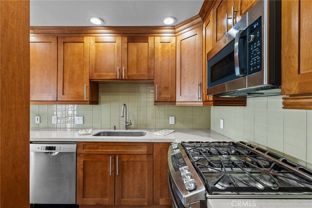 kitchen featuring appliances with stainless steel finishes, light stone countertops, sink, and tasteful backsplash