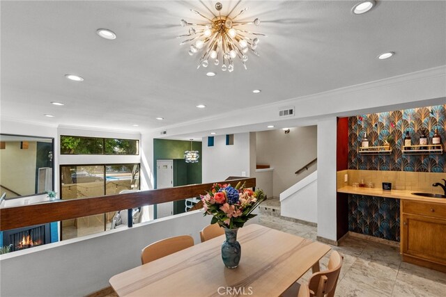 dining room featuring an inviting chandelier, ornamental molding, and sink