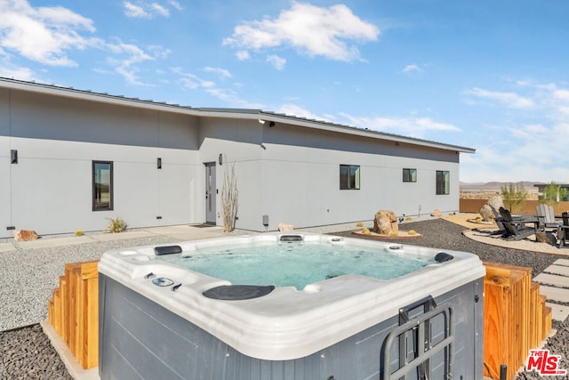 rear view of property featuring a patio area and a hot tub