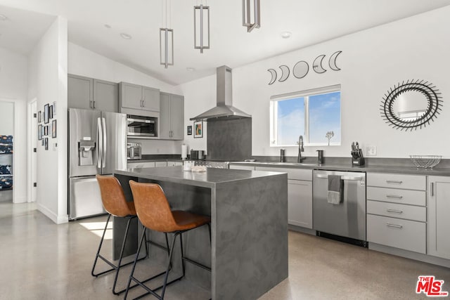 kitchen with wall chimney range hood, a kitchen island, sink, lofted ceiling, and appliances with stainless steel finishes