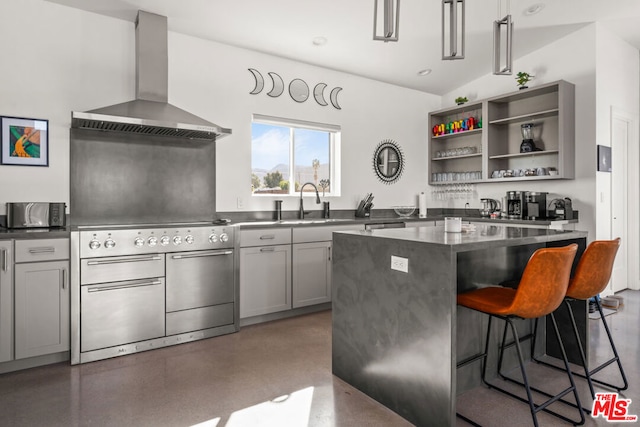 kitchen with a kitchen island, sink, wall chimney range hood, high end stainless steel range, and a kitchen bar