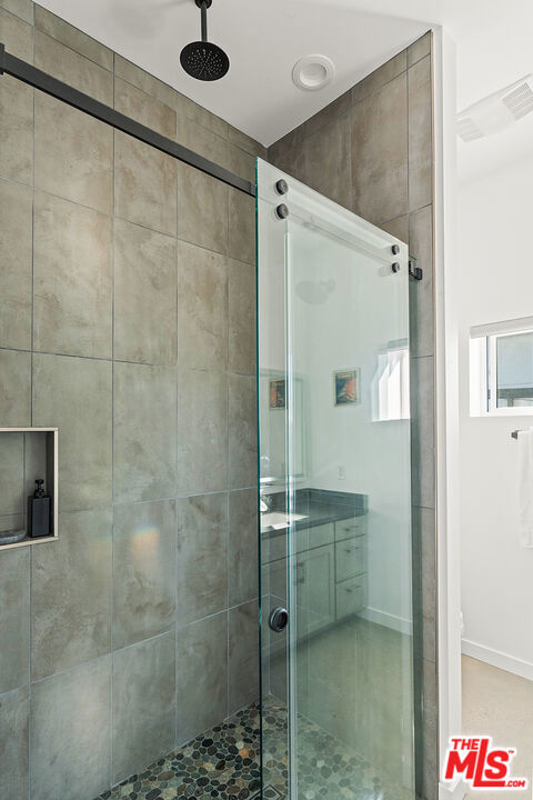 bathroom featuring a shower with door and vanity