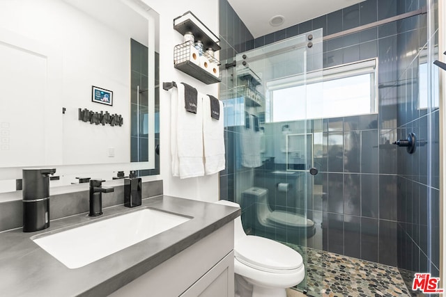 bathroom with a shower with door, vanity, and toilet