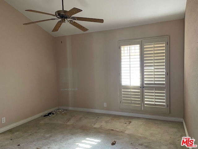 carpeted spare room featuring ceiling fan and vaulted ceiling