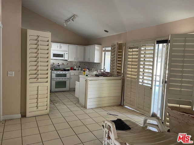 kitchen with light tile patterned flooring, white appliances, vaulted ceiling, decorative backsplash, and white cabinets