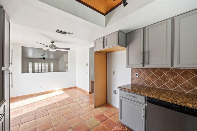 kitchen featuring light tile patterned floors, stainless steel dishwasher, ceiling fan, dark stone counters, and decorative backsplash