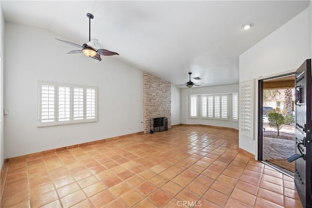 unfurnished living room with vaulted ceiling, a stone fireplace, light tile patterned floors, and ceiling fan