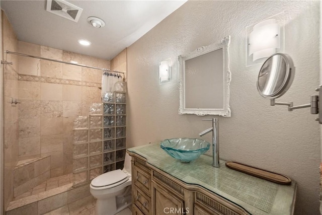 bathroom with tile patterned flooring, vanity, walk in shower, and toilet