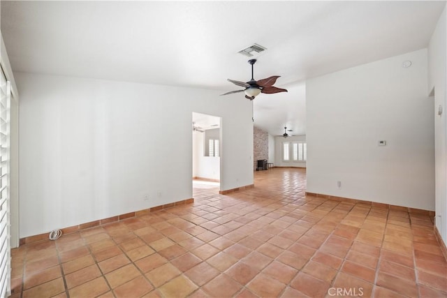 empty room featuring lofted ceiling, light tile patterned floors, a fireplace, and ceiling fan