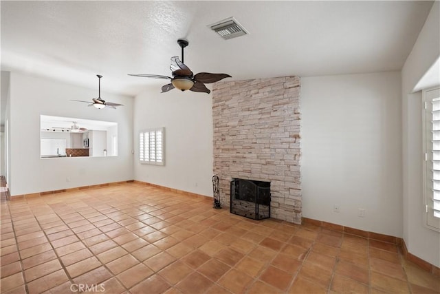 unfurnished living room featuring ceiling fan, a fireplace, and light tile patterned floors