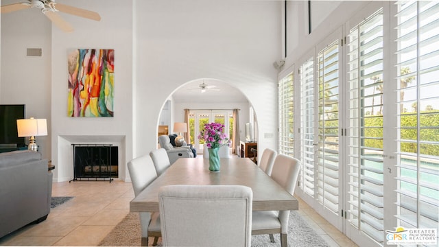 dining room with ceiling fan, light tile patterned floors, and a high ceiling