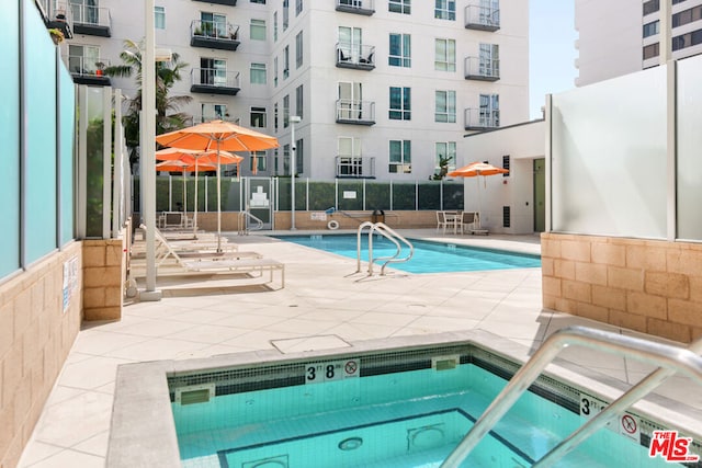 view of swimming pool featuring a patio and a hot tub