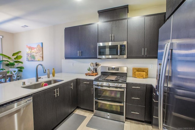 kitchen with sink, stainless steel appliances, and light hardwood / wood-style floors