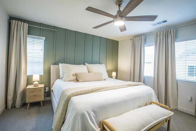 carpeted bedroom featuring multiple windows and ceiling fan