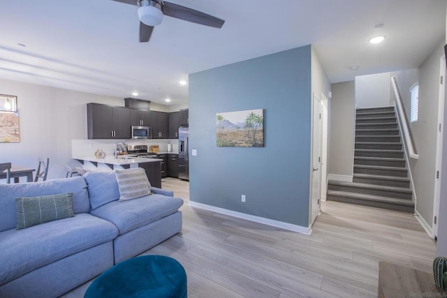 living room featuring ceiling fan, sink, and light hardwood / wood-style flooring