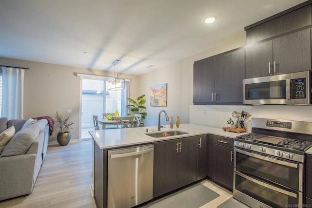 kitchen featuring a wealth of natural light, sink, stainless steel appliances, kitchen peninsula, and decorative light fixtures