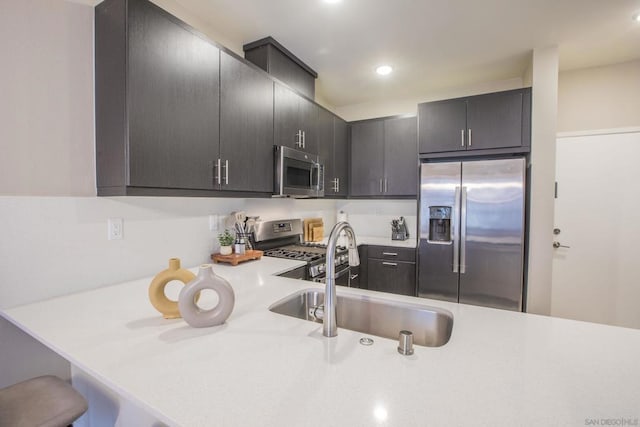 kitchen with a kitchen bar, stainless steel appliances, kitchen peninsula, and sink