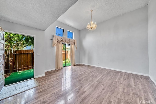 interior space featuring light wood-type flooring, a textured ceiling, and a notable chandelier