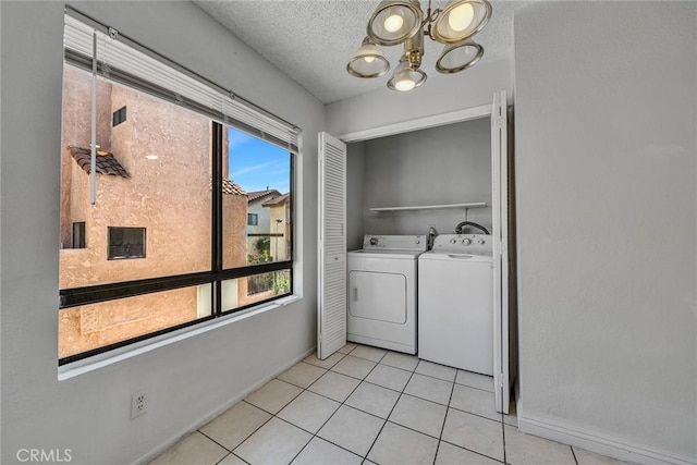 clothes washing area featuring washing machine and dryer, an inviting chandelier, light tile patterned floors, and a textured ceiling