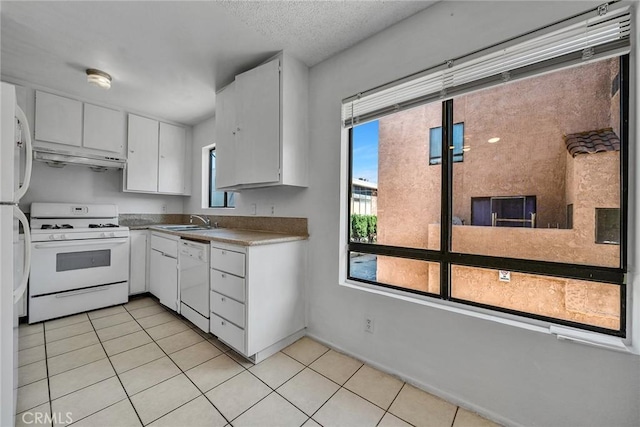 kitchen featuring white appliances, a textured ceiling, white cabinetry, sink, and light tile patterned flooring