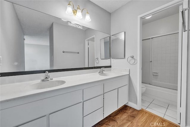 full bathroom featuring toilet, combined bath / shower with glass door, tile patterned floors, a textured ceiling, and vanity