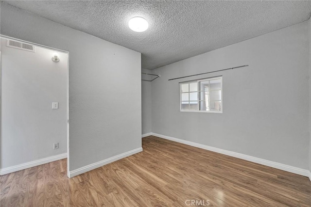 unfurnished room featuring light hardwood / wood-style floors and a textured ceiling