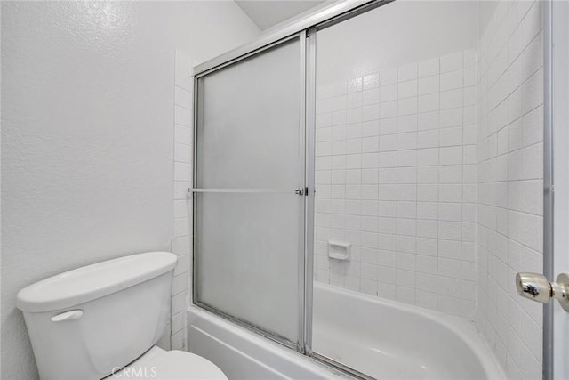 bathroom with toilet and shower / bath combination with glass door