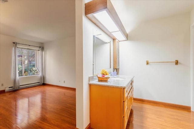 interior space featuring light hardwood / wood-style floors, sink, light brown cabinets, and a baseboard heating unit