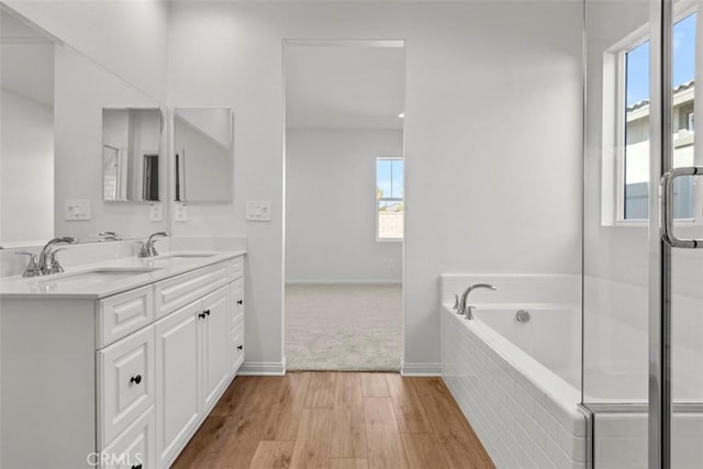 bathroom featuring tiled bath, vanity, and hardwood / wood-style flooring