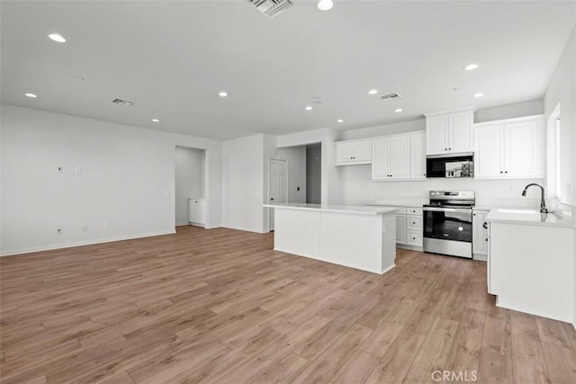 kitchen featuring electric stove, white cabinetry, sink, and light wood-type flooring