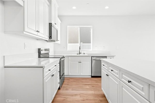 kitchen featuring light hardwood / wood-style flooring, white cabinets, stainless steel appliances, and sink