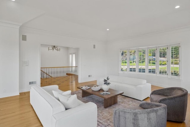 living room featuring crown molding, a notable chandelier, and light wood-type flooring