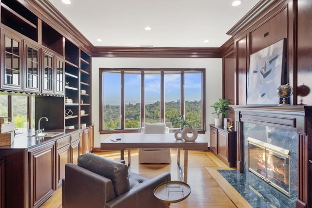 office area featuring sink, a high end fireplace, ornamental molding, and light wood-type flooring