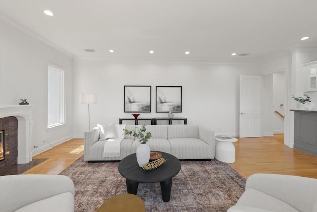 living room featuring light hardwood / wood-style flooring, ornamental molding, and a premium fireplace