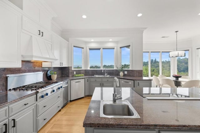 kitchen featuring a kitchen island with sink, sink, decorative light fixtures, and appliances with stainless steel finishes