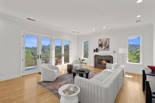 living room with crown molding, light hardwood / wood-style flooring, a high end fireplace, and french doors