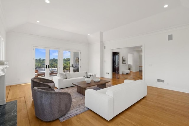 living room featuring vaulted ceiling, french doors, and light wood-type flooring